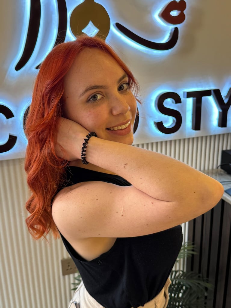 Woman with red hair posing and smiling in front of neon sign display